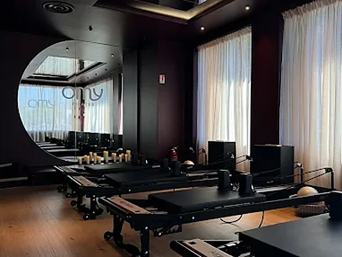 Salle de Reformers du studio OMY Pilates, miroir rond et grandes fenêtres